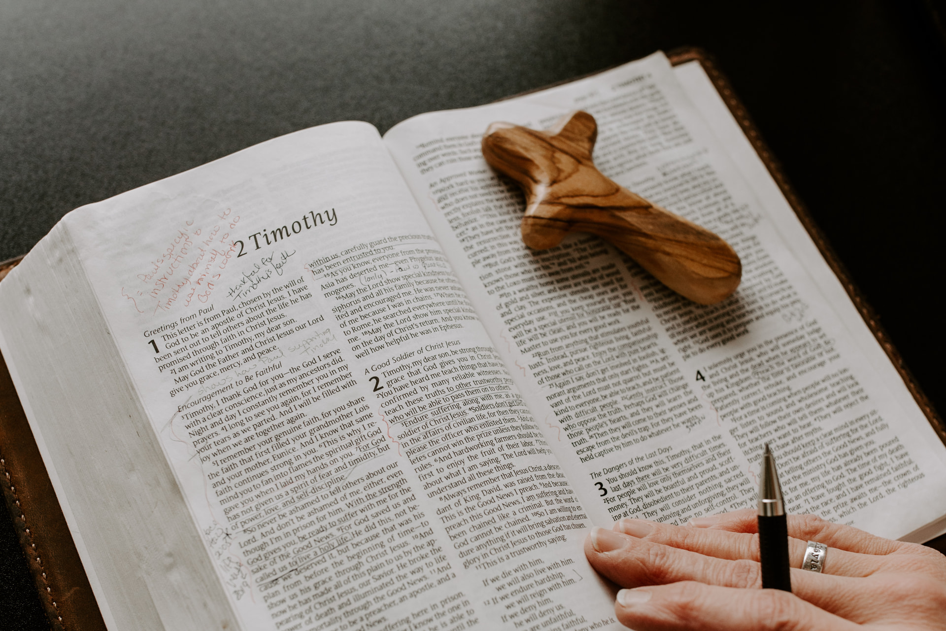 An open Bible with a small wooden cross resting on the pages for Christian spiritual direction